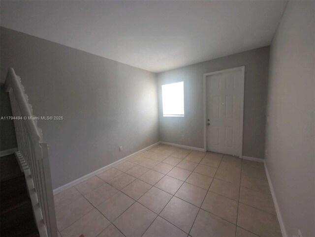 spare room with baseboards and light tile patterned flooring