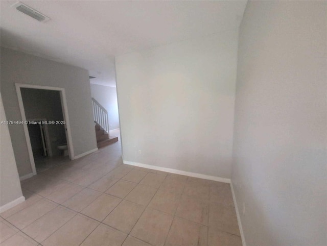empty room with baseboards, stairs, light tile patterned flooring, and visible vents