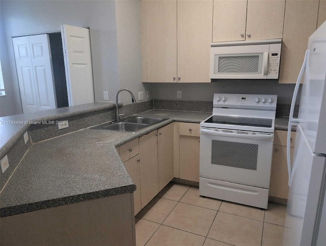 kitchen featuring dark countertops, a sink, white appliances, a peninsula, and light tile patterned floors
