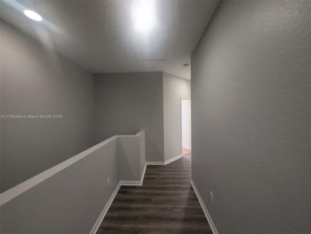 hallway with baseboards, dark wood-style flooring, and an upstairs landing