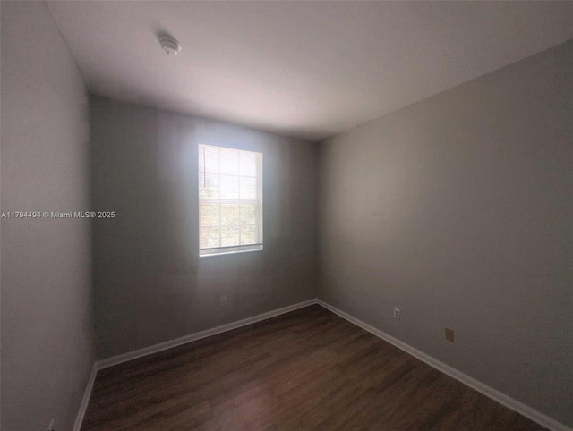 empty room with baseboards and dark wood-style floors