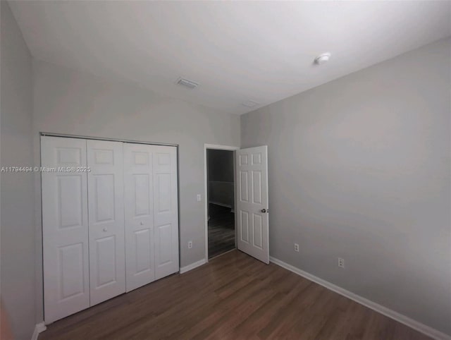 unfurnished bedroom with baseboards, visible vents, wood finished floors, and a closet
