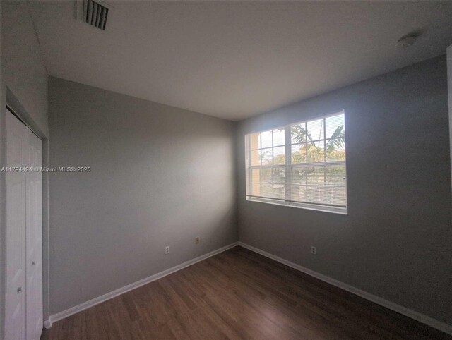 empty room with baseboards, dark wood finished floors, and visible vents