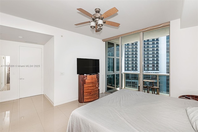 bedroom featuring expansive windows, a ceiling fan, baseboards, and tile patterned flooring