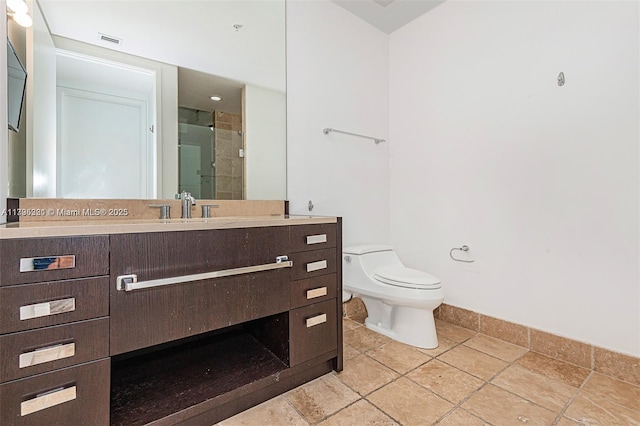 bathroom with vanity, toilet, baseboards, a shower stall, and visible vents