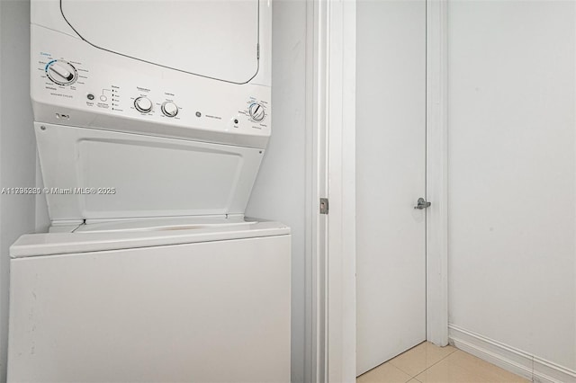 clothes washing area featuring laundry area, stacked washing maching and dryer, and light tile patterned floors