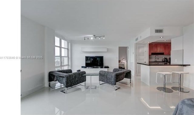tiled living room featuring track lighting and visible vents