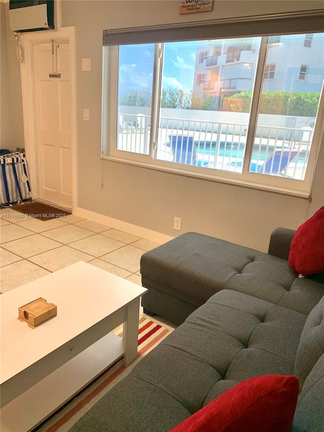 living area with baseboards, tile patterned flooring, and an AC wall unit