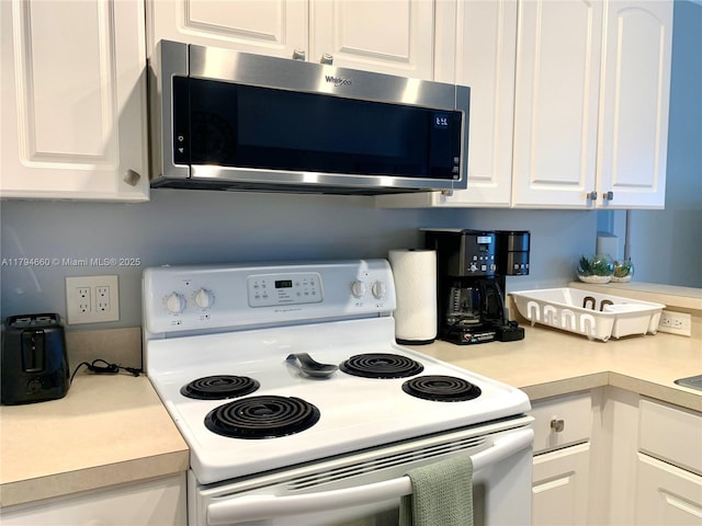 kitchen with white cabinets, stainless steel microwave, white electric range oven, and light countertops