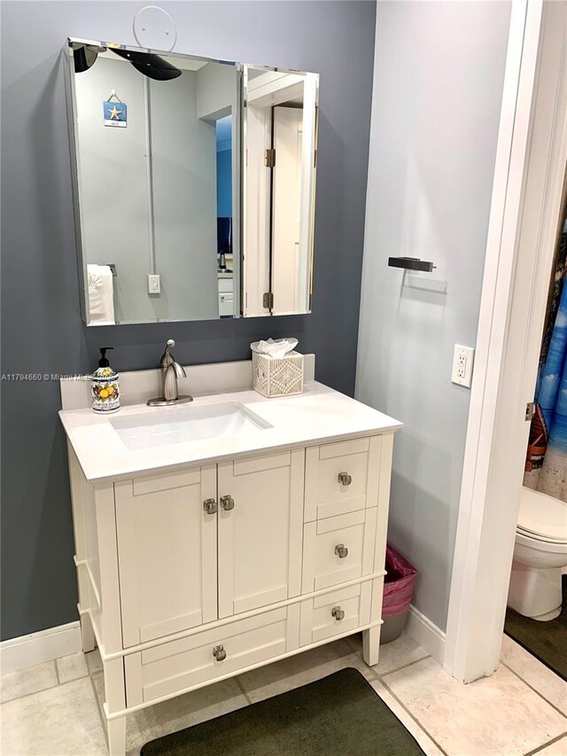 bathroom with vanity, baseboards, toilet, and tile patterned floors