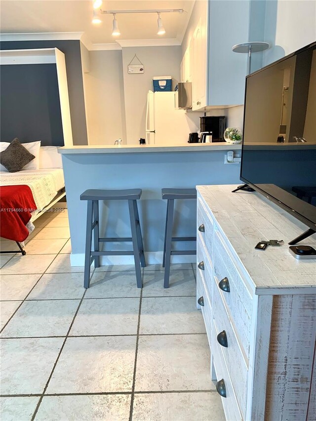 kitchen featuring crown molding, track lighting, freestanding refrigerator, stainless steel microwave, and a peninsula