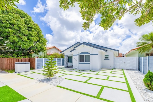 view of front of house with a fenced backyard, a gate, stucco siding, and a patio area