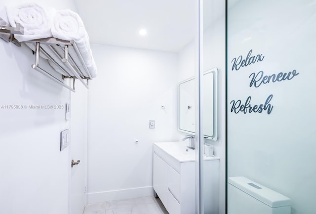 bathroom featuring toilet, baseboards, marble finish floor, and vanity