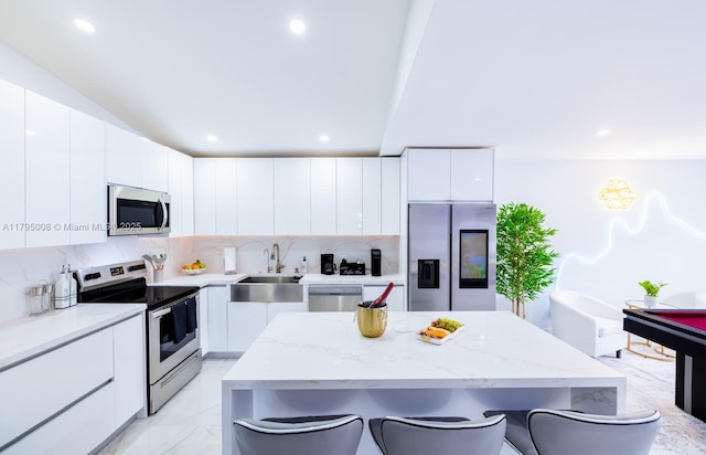 kitchen with a breakfast bar, modern cabinets, white cabinets, a sink, and appliances with stainless steel finishes