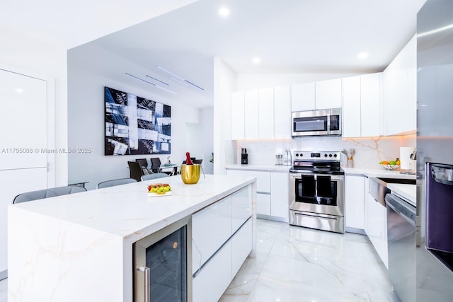 kitchen with beverage cooler, appliances with stainless steel finishes, white cabinetry, and modern cabinets