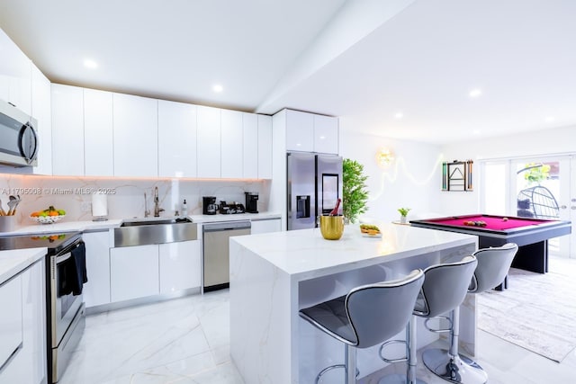 kitchen featuring a sink, stainless steel appliances, white cabinetry, a kitchen island, and modern cabinets