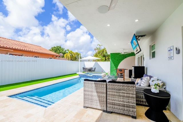 view of swimming pool featuring a pool with connected hot tub, ceiling fan, outdoor lounge area, a fenced backyard, and a patio area