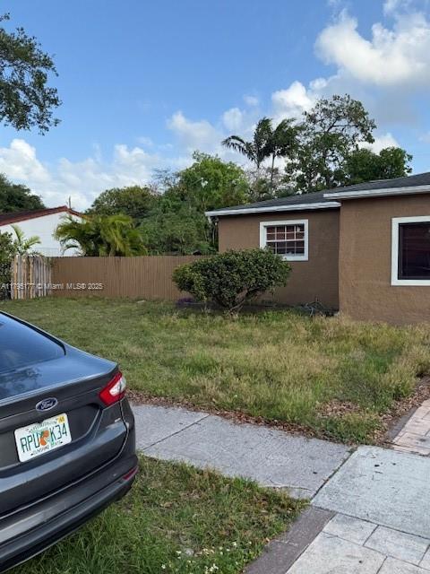 view of home's exterior with a yard, fence, and stucco siding