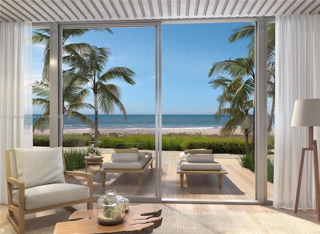 sitting room featuring a water view, a view of the beach, and expansive windows