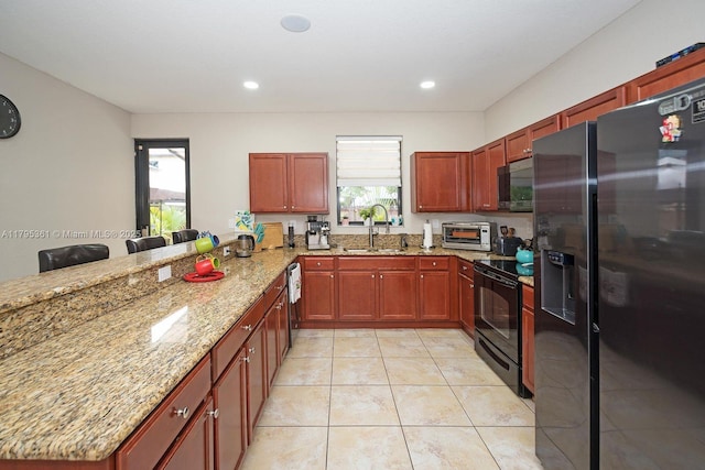 kitchen with light stone counters, refrigerator with ice dispenser, a sink, a peninsula, and black range with electric stovetop