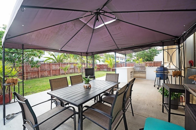 view of patio featuring a gazebo, area for grilling, exterior kitchen, a fenced backyard, and outdoor dining area