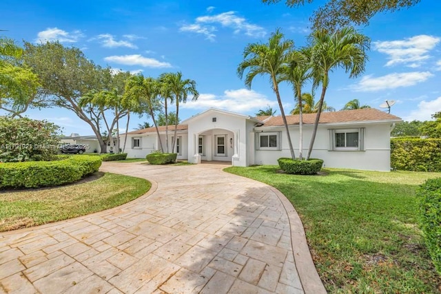 view of front of property with curved driveway, a front lawn, and stucco siding
