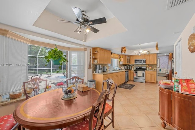 dining area featuring light tile patterned floors, a raised ceiling, ceiling fan, and visible vents