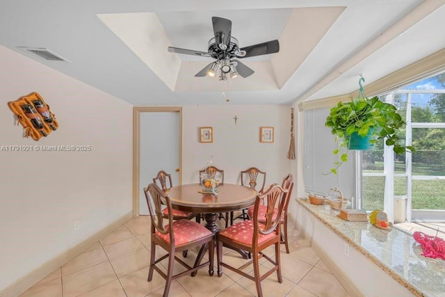 dining area featuring a ceiling fan, visible vents, light tile patterned floors, baseboards, and a tray ceiling