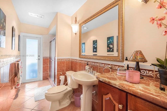 full bathroom featuring tile patterned flooring, toilet, a wainscoted wall, tile walls, and a stall shower