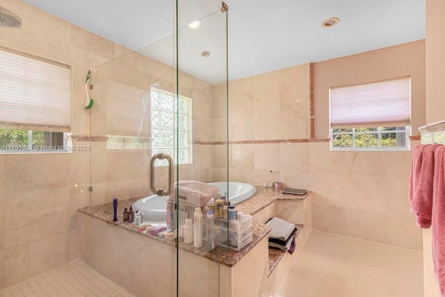 bathroom with tile patterned floors, tile walls, a shower stall, and a garden tub
