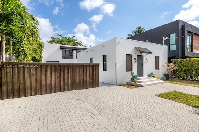contemporary home with fence and stucco siding