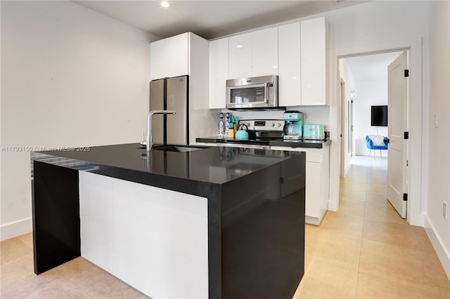 kitchen featuring white cabinetry, dark countertops, appliances with stainless steel finishes, and a sink