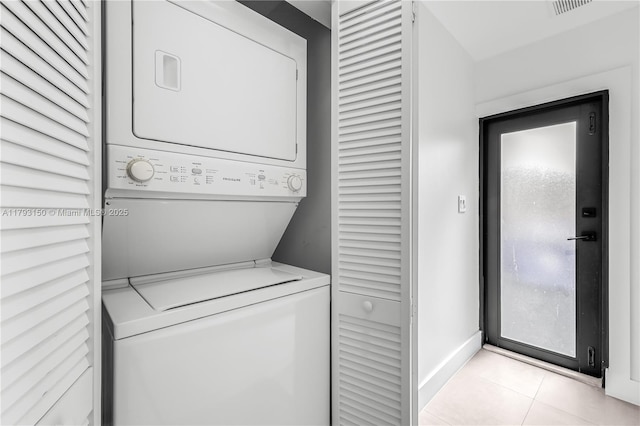 laundry area featuring light tile patterned floors, baseboards, laundry area, and stacked washer / drying machine