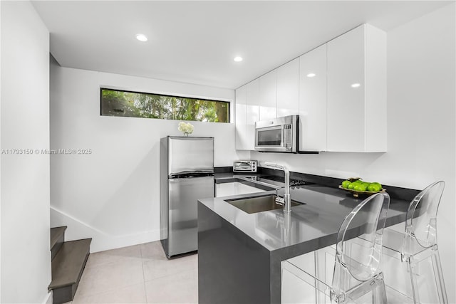 kitchen with a peninsula, dark countertops, modern cabinets, and appliances with stainless steel finishes
