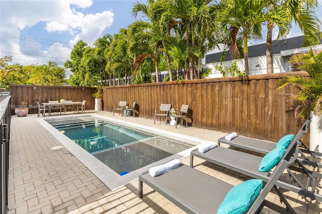 view of swimming pool with a patio, outdoor dining area, and fence