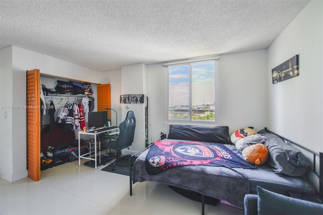 bedroom featuring a closet, a textured ceiling, and tile patterned flooring