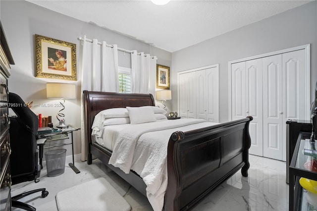 bedroom featuring marble finish floor and multiple closets