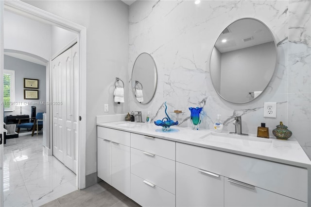 bathroom with marble finish floor, visible vents, a sink, and double vanity
