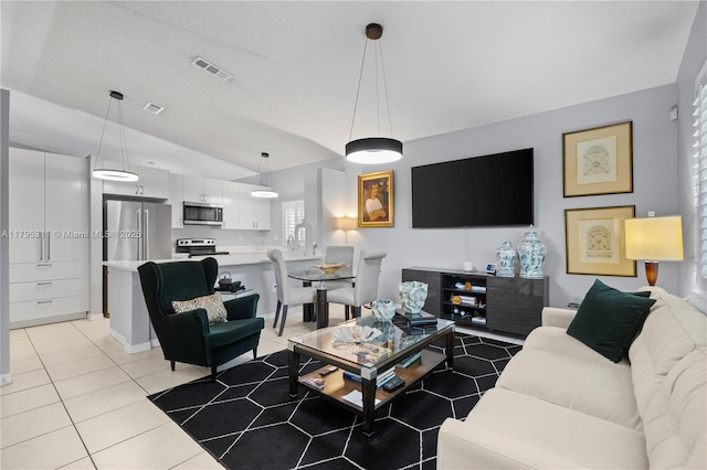 living area with vaulted ceiling, light tile patterned flooring, and visible vents