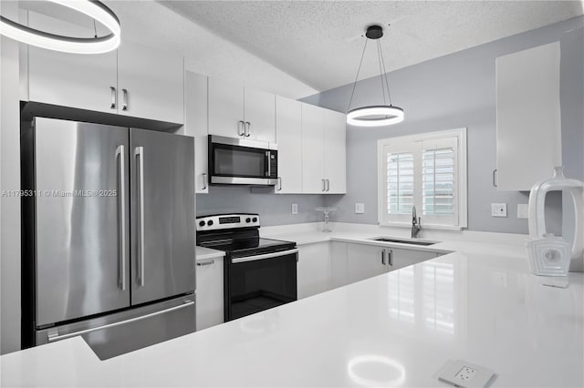 kitchen with a sink, a textured ceiling, light countertops, white cabinets, and appliances with stainless steel finishes