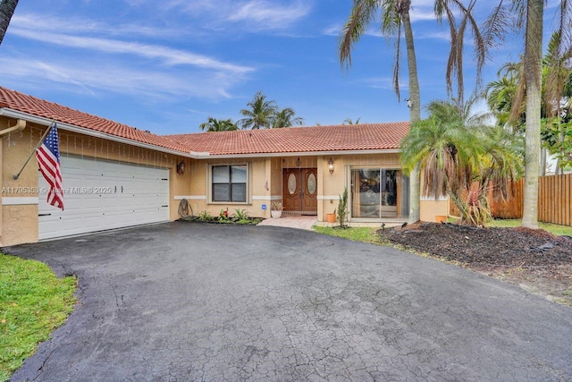 single story home featuring an attached garage, aphalt driveway, a tile roof, and stucco siding