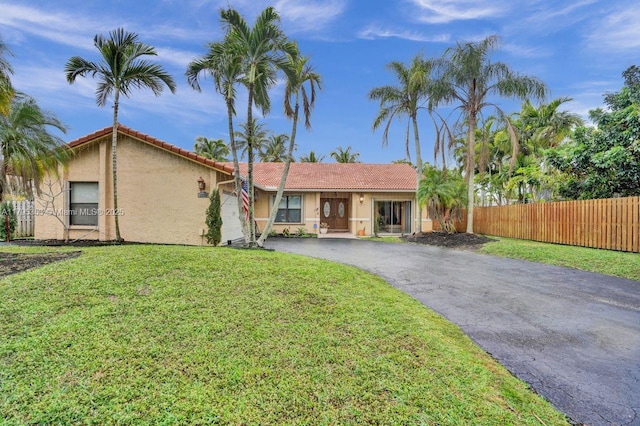 ranch-style home with fence, aphalt driveway, a front lawn, and stucco siding