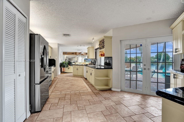 kitchen with open shelves, dark countertops, cream cabinetry, french doors, and appliances with stainless steel finishes