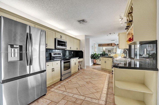 kitchen featuring visible vents, cream cabinets, open shelves, a sink, and stainless steel appliances