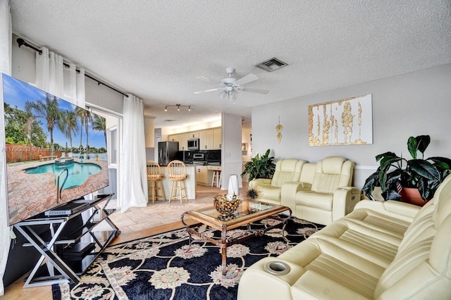 living room with visible vents, a textured ceiling, and ceiling fan