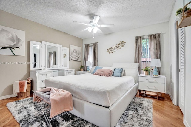 bedroom featuring a ceiling fan, a textured ceiling, and light wood-style flooring