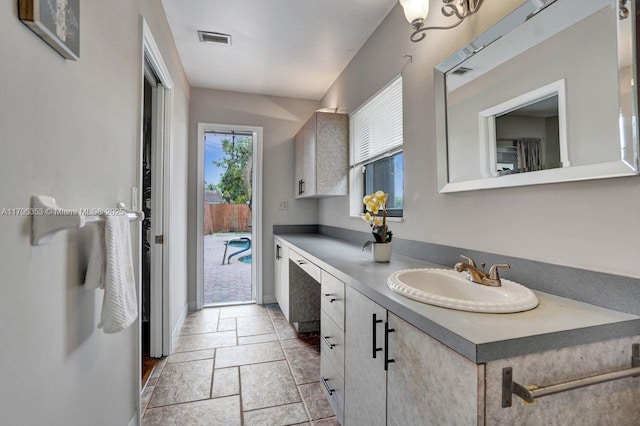 bathroom with visible vents, baseboards, stone tile flooring, and vanity