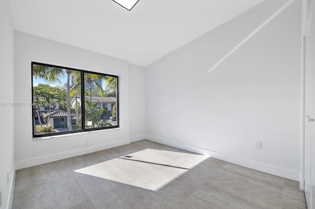 carpeted empty room featuring baseboards and vaulted ceiling