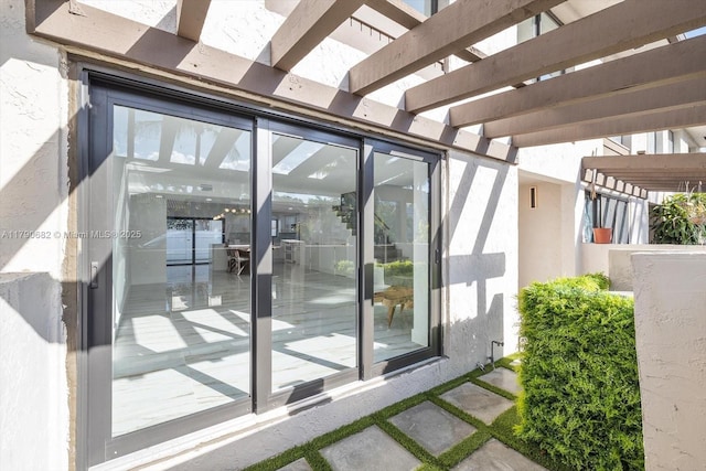 doorway to property featuring a pergola and stucco siding