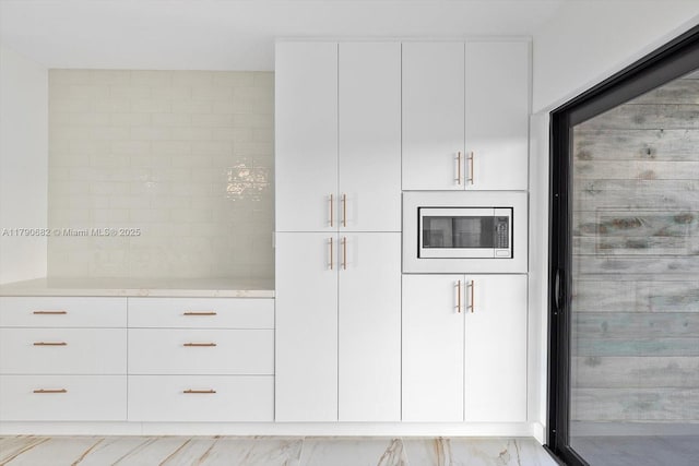 kitchen featuring white cabinets, stainless steel microwave, and modern cabinets